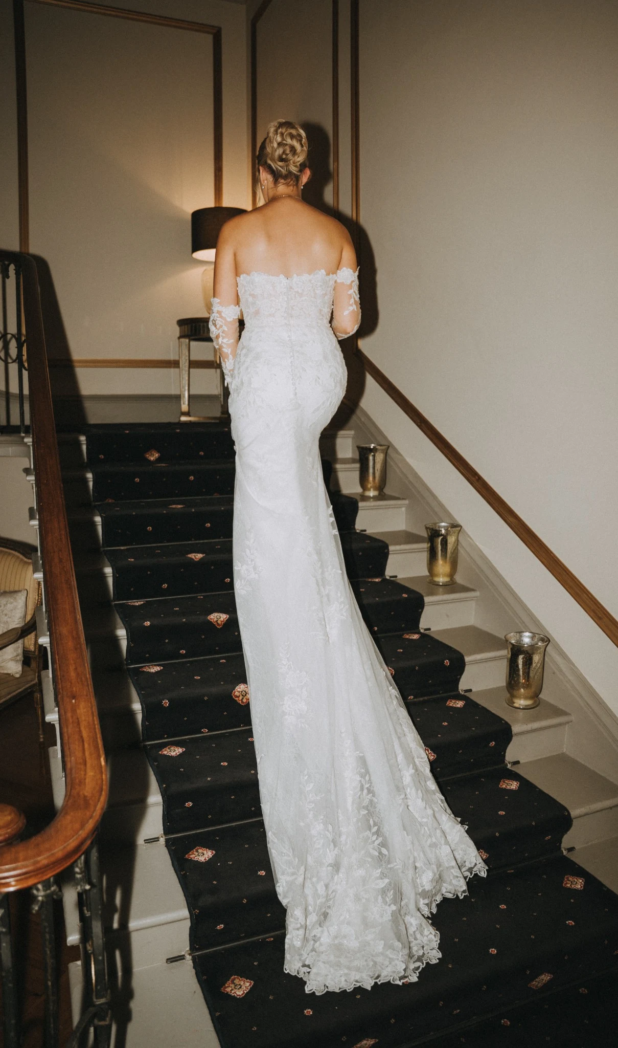 Anna & Tyrone bridal hair at Rise Hall — the bride on the staircase, her hair dressed low.