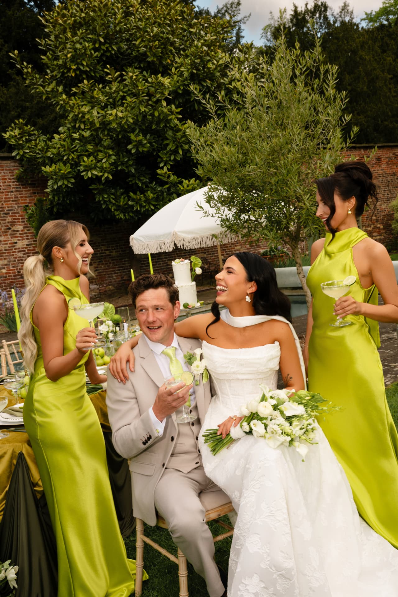 Bride laughing with the groom and two bridesmaids in lime satin gowns.