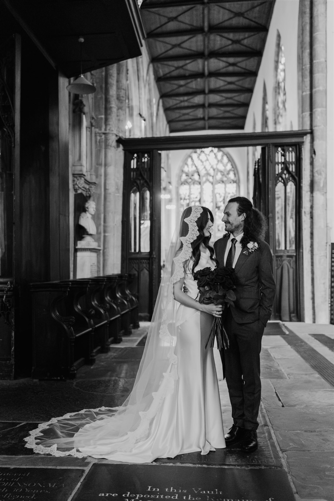 Bride and groom standing together inside Hull Minster, looking at each other.
