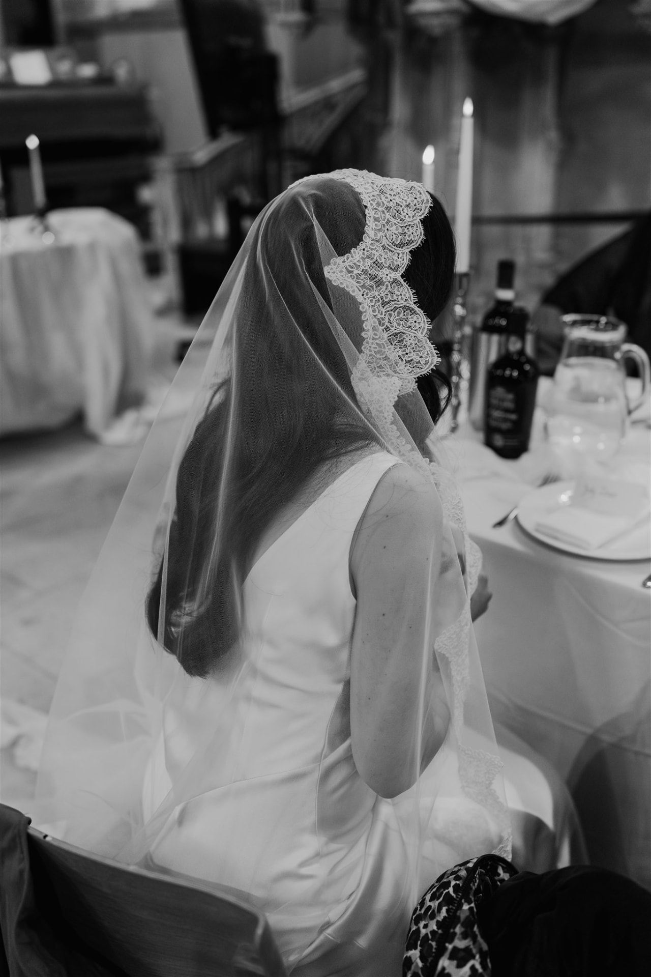 Black and white image of the bride from behind, showing a lace-trimmed veil.